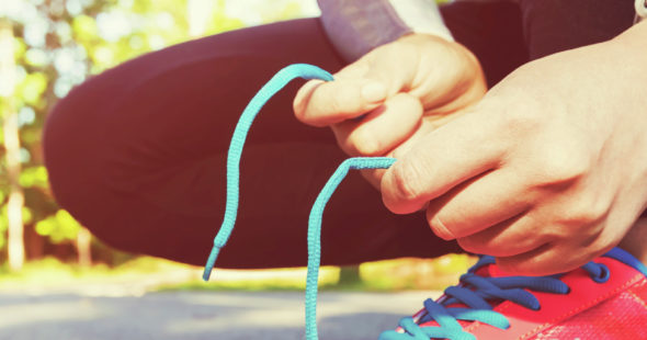 Female joffer tying her running shoes for a jog with a smartwatch on her wrist