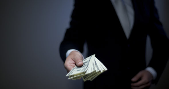 Anonymous business person holding out a stack of 100 dollar bills