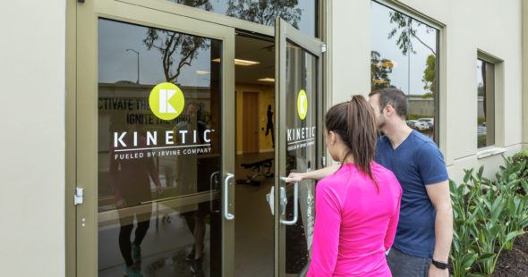 A man and woman walking into the KINETIC fitness center located ar Irvine Business Center in Irvine, CA