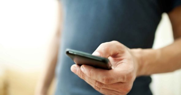 Close up photo of a man holding a black smartphone