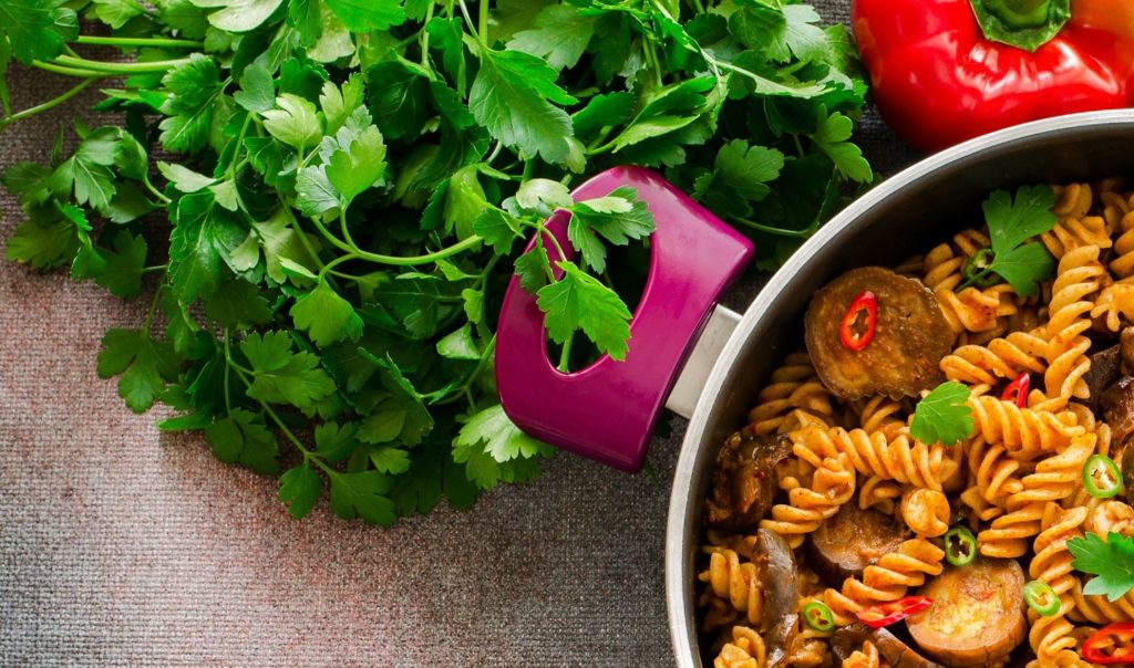 Spiced fusilli pasta in a pot with fresh parsley and bell pepper